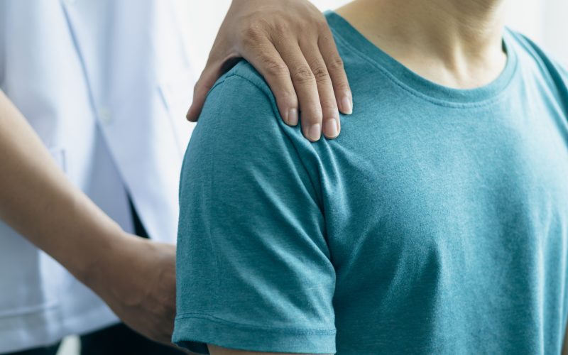 A man with back pain sees a doctor so the doctor is diagnosing men's back pain and shoulder pain.
